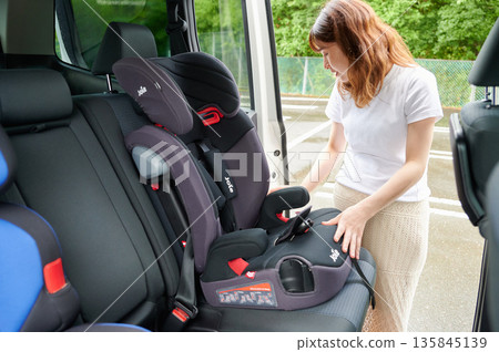 Pregnant woman installing a child seat Pregnant woman installing a child seat 135845139
