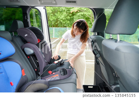 Pregnant woman installing a child seat 135845155