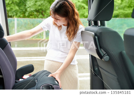 Pregnant woman installing a child seat 135845181