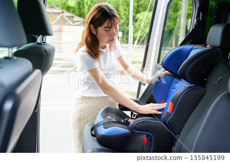 Pregnant woman installing a child seat 135845199