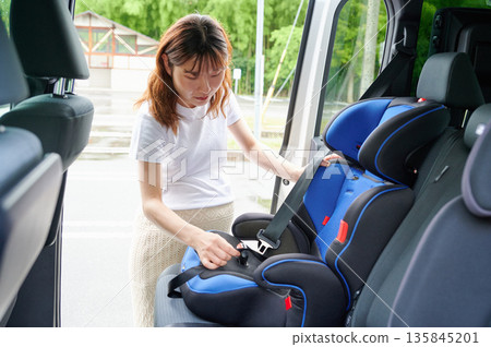 Pregnant woman installing a child seat Pregnant woman installing a child seat 135845201