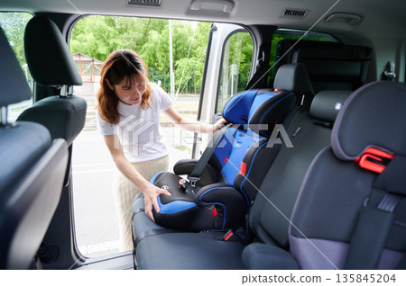 Pregnant woman installing a child seat Pregnant woman installing a child seat 135845204