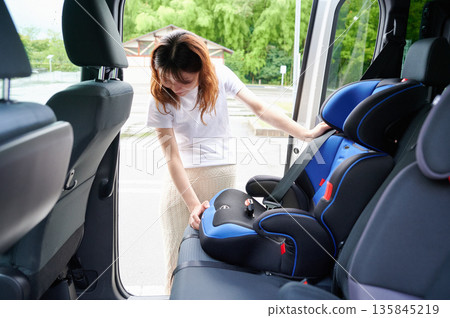 Pregnant woman installing a child seat Pregnant woman installing a child seat 135845219