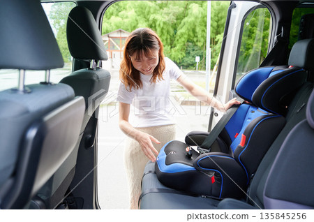 Pregnant woman installing a child seat 135845256