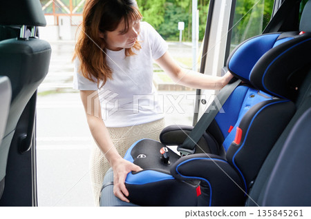 Pregnant woman installing a child seat Pregnant woman installing a child seat 135845261