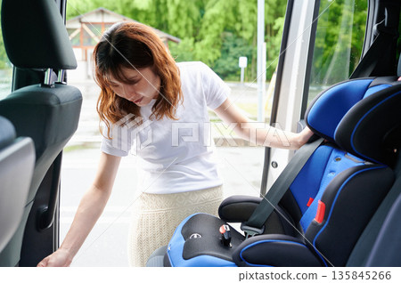 Pregnant woman installing a child seat Pregnant woman installing a child seat 135845266