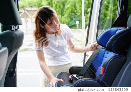Pregnant woman installing a child seat 135845269