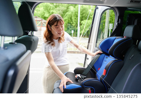 Pregnant woman installing a child seat Pregnant woman installing a child seat 135845275