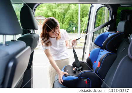 Pregnant woman installing a child seat 135845287
