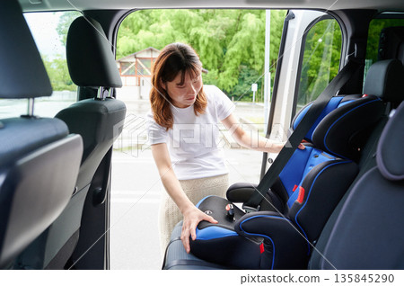 Pregnant woman installing a child seat 135845290