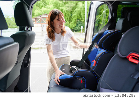 Pregnant woman installing a child seat 135845292