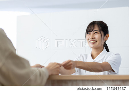 一位身穿白大褂的女士在接待處收到一張賀卡。 135845687