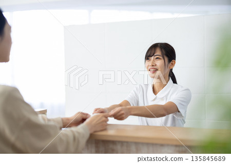 一位身穿白大褂的女士在接待處收到一張賀卡。 135845689