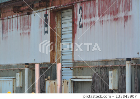 The rusty shutters on the wall of the seaside warehouse remain closed forever 135845907