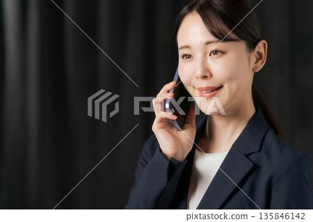 A woman in a suit in front of a black curtain A woman in a suit in front of a black curtain 135846142
