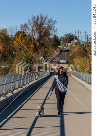 A woman is walking her dog on a bridge 135846249