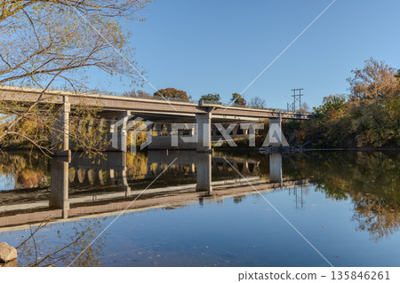 A bridge spans a river with a calm, reflective surface A bridge spans a river with a calm, reflective surface 135846261