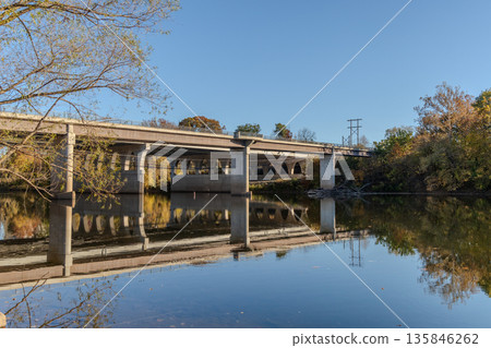 A bridge spans a river with a calm, reflective surface A bridge spans a river with a calm, reflective surface 135846262