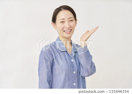 A woman in pajamas pointing to the right with her palm on a white background A woman in pajamas pointing to the right with her palm on a white background 135846354