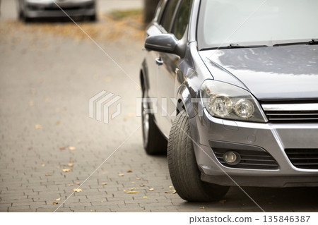 Gray shiny car parked in quiet area on asphalt road on blurred bokeh background on bright sunny day. Transportation and parking concept. 135846387
