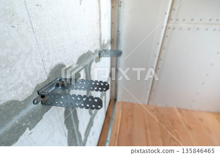 Unfinished brick wall in a room under construction prepared for drywall plates frame installation. 135846465