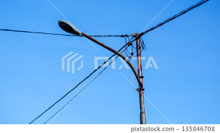 Rusty Street Lamp Pole with Messy Electrical Cables and Blue Sky Rusty Street Lamp Pole with Messy Electrical Cables and Blue Sky 135846708