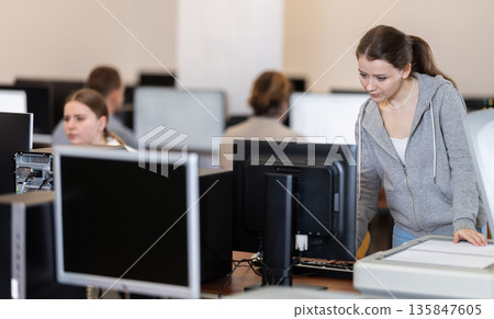 Girl puts paper document into copier, makes copy using office appliances Girl puts paper document into copier, makes copy using office appliances 135847605