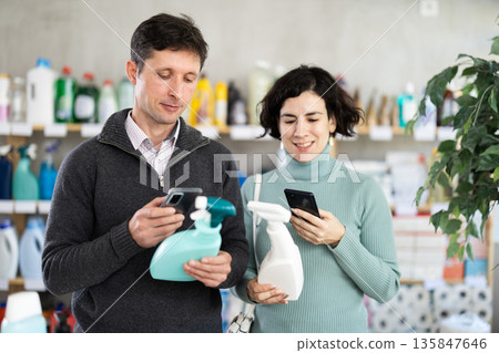 Husband and wife scan cleaning sprays on phone 135847646