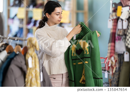 Armenian woman choosing a sweater in a clothing store Armenian woman choosing a sweater in a clothing store 135847654