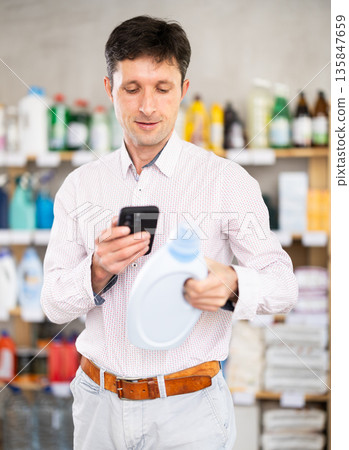 man scans the barcode of the label of a detergent 135847659