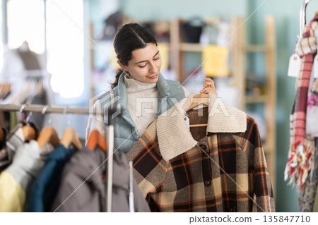 Young woman chooses coat in clothing store 135847710