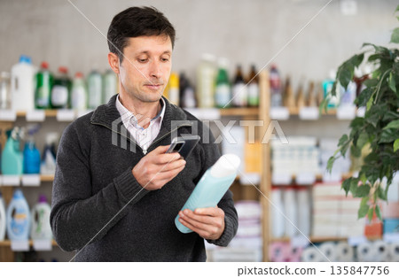 Checking expiration date of shampoo or shower gel - male shopper scans QR code on label of shampoo using smartphone Checking expiration date of shampoo or shower gel - male shopper scans QR code on label of shampoo using smartphone 135847756