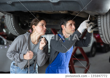 Girl is present while car is being repaired in workshop 135847772