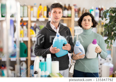 Among shop windows, married couple buyer leisurely examines goods and chooses laundry conditioner Among shop windows, married couple buyer leisurely examines goods and chooses laundry conditioner 135847792