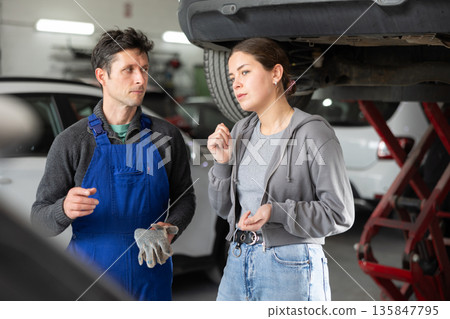 Male auto mechanic discussing with woman the cost and time to repair her car at car service 135847795