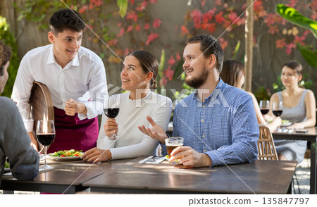 Waiter talking to restaurant guests - taking orders for food and drinks Waiter talking to restaurant guests - taking orders for food and drinks 135847797