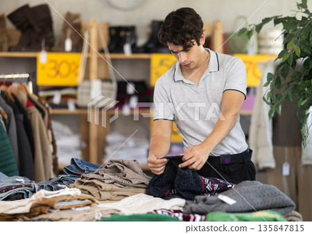 In chain shop, young man choose sweater In chain shop, young man choose sweater 135847815
