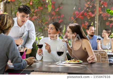 Waiter talking to restaurant guests - taking orders for food and drinks 135847816