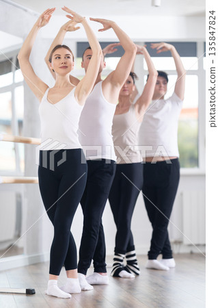 Group of dancers stand in fifth position at barre Group of dancers stand in fifth position at barre 135847824