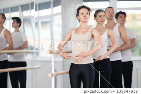 Group of dancers stand in first position at barre 135847919