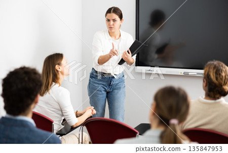 Portrait of young businesswoman standing near interactive board and participating in corporate seminar in auditorium Portrait of young businesswoman standing near interactive board and participating in corporate seminar in auditorium 135847953