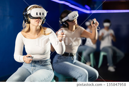 Two girls wearing virtual reality glasses participate in game with opponents Two girls wearing virtual reality glasses participate in game with opponents 135847958