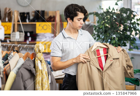 In chain shop, guy choose rain jacket In chain shop, guy choose rain jacket 135847966