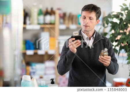 Man sniffs fragrance of perfume, chooses scent spray with pleasant smell Man sniffs fragrance of perfume, chooses scent spray with pleasant smell 135848003