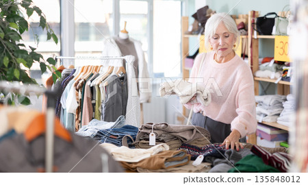 Regular customer senior woman chooses color and style of sweater Regular customer senior woman chooses color and style of sweater 135848012