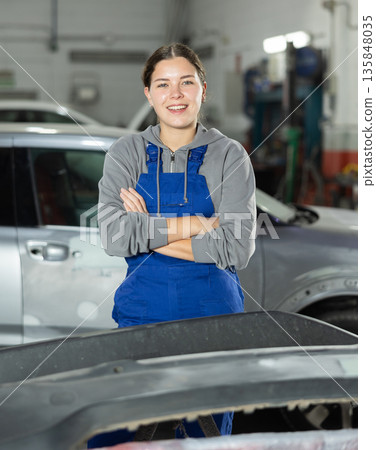 Young woman auto mechanic polishes body parts by car buffer polisher machine tool Young woman auto mechanic polishes body parts by car buffer polisher machine tool 135848035