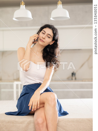Young woman talking on phone in kitchen 135848051
