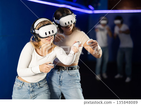 Two girls wearing virtual reality glasses participate in game with opponents Two girls wearing virtual reality glasses participate in game with opponents 135848089