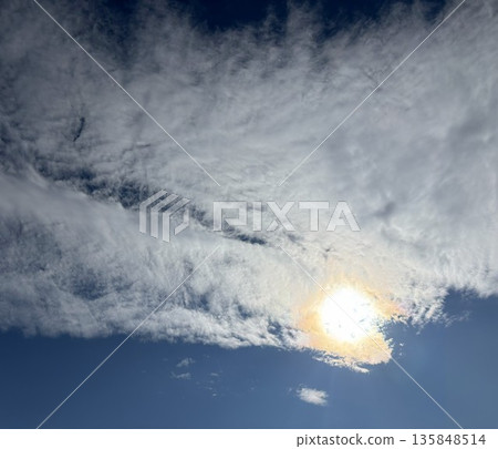A fantastic skyscape created by a beautiful veil of thin clouds spreading across a clear blue sky and the powerful sunlight shining through the clouds. 135848514