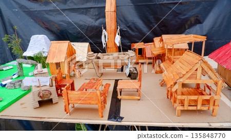 Wide View of Handmade Miniature Village with Wooden Houses and Cardboard Ship, Creative Sustainable Crafts Display, Detailed Scale Model 135848770